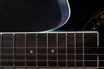 guitar neck with strings close-up on a black wooden background
