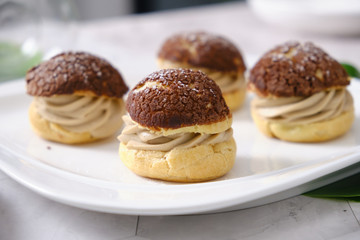 choux cream or cream puff or French profiteroles with fresh cream set on cafe table.