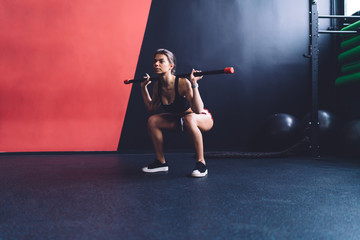 Athletic woman exercising with body bar in gym