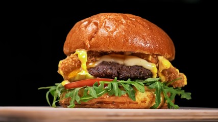 Craft burger is cooking on black background in black food gloves. Consist: sauce, arugula, tomato, red onion rings fries, cucumber, cheese, air bun and marble meat beef. Not made ideal. Looks real