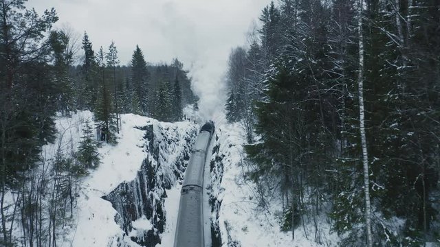 Aerial view steam train running backward in winter forest