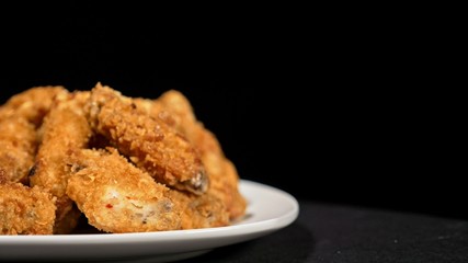 Cool beautiful fresh juicy cooked chicken wings in breading. Buffalo wings spread on food white plate in table. Very tasty and beautiful. Cooking with deep fryer fry machine.