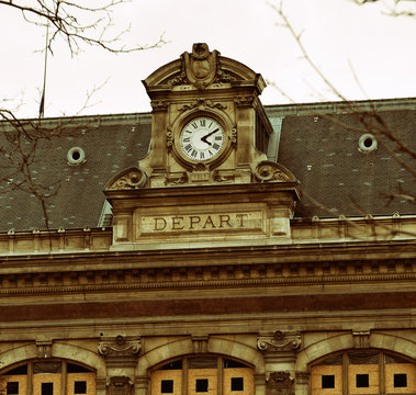 Facade of Haussmannian style building from 1867 with clock and "departure" text in French.