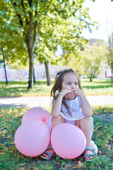offended sad lonely child girl sitting on grass with balloons
