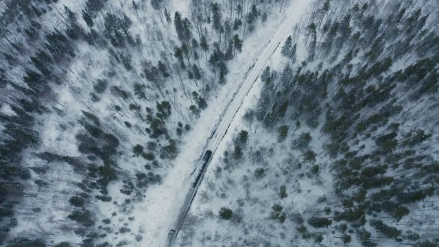 Aerial view retro locomotive running on railway in winter forest. Winter xmas season. Snow covered pine and spruce around railway