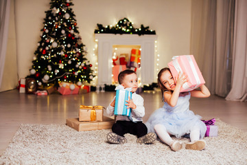 Fototapeta na wymiar little boy and girl open Christmas presents new year winter Christmas tree