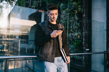 Modern cool man using smartphone on street