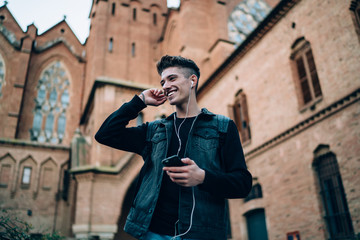 Happy young man standing with earphones and smartphone