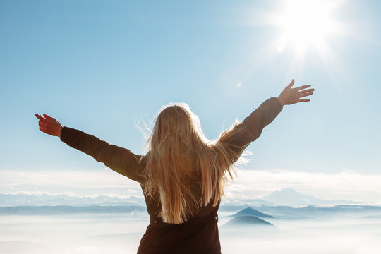 Beautiful happy woman enjoying mountains landscape with  outstretched raised arms to the sky
