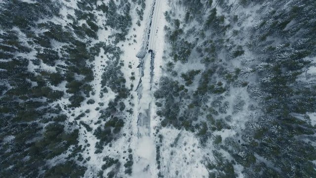 Aerial top view old steam train running in winter snowy forest. Top down view Heritage historic steam locomotive