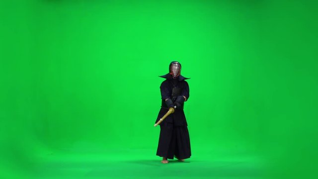 Masculine Kendo warrior practicing martial art with the bamboo bokken on green screen. Slow motion