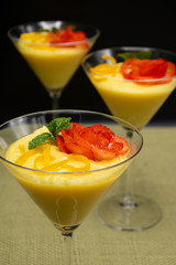 Vanilla Pudding with lemon and strawberry garnish in Martini glass with black background.