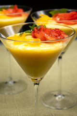 Vanilla Pudding with lemon and strawberry garnish in Martini glass with black background.