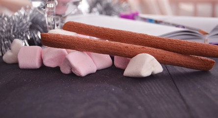 Hot winter drink with candies, Christmas or New Year decorations, dark background, rustic style, colored marshmallows.