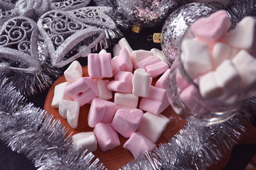 Hot winter drink with candies, Christmas or New Year decorations, dark background, rustic style, colored marshmallows.