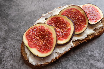 One sandwich with figs, cheese, honey and nuts on a gray background. Homemade. Casual autumn kitchen. The concept of healthy eating.