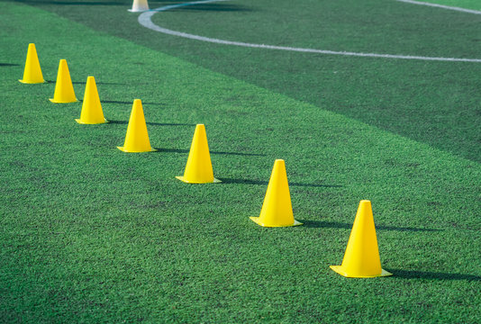 Yellow sport training cones marker on soccer green grass pitch for children football training session