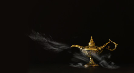 Image of magical mysterious aladdin lamp with glitter sparkle smoke over black background. Lamp of...