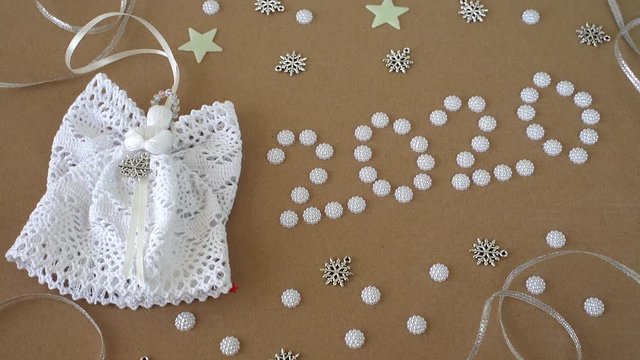 Christmas 2020 decorations on paper background. Angels, text "2020", lace and pearls