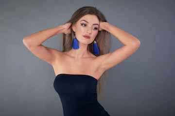Fototapeta premium Woman with beauty long brown hair, posing at studio. long earrings classic blue