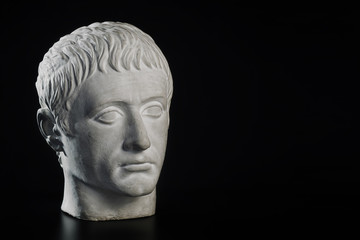 Gypsum statue of Apollo's head on a black background. Gypsum head of emperor Germanicus. Marble bust of Julius Caesar isolated on black. Space for text.