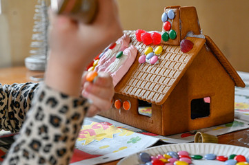 child decorating gingerbread house with candy and icing