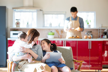 ソファーに座りタブレットPCを見る親子