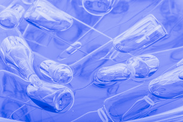 Glass medical ampoule vial for injection. Medicine is liquid sodium chloride with of aqueous solution in ampulla. Close up. Bottles ampule multicolor on background color and water. Human plasma.