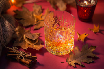 A glass of whiskey or bourbon, spices and decoration on dark background