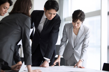 製図を使って打ち合わせをするビジネスマン