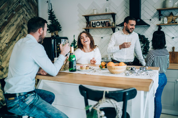 Obraz premium Friends laughing at Christmas table drinking champagne