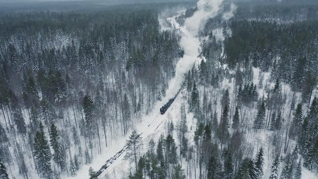 Aerial view steam retro train running on snowy railway in winter forest