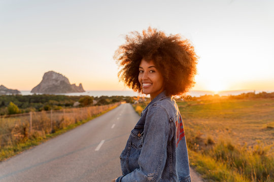 Young woman standing on street and looking at camera at sunset, Ibiza