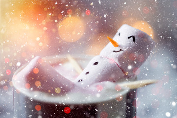 Cute little snowman made from marshmallows bathing in a mug with hot chocolate 