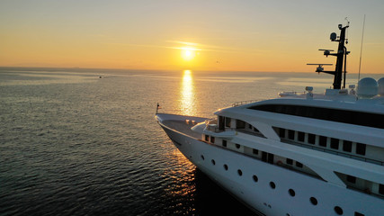 Aerial drone photo of luxury yacht docked in Aegean deep blue sea at sunset with beautiful golden...