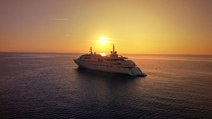 Obraz premium Aerial drone photo of luxury yacht docked in Aegean deep blue sea at sunset with beautiful golden colours, Greece