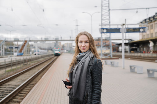 Portrait of smiling young woman with smartphone standing on platform