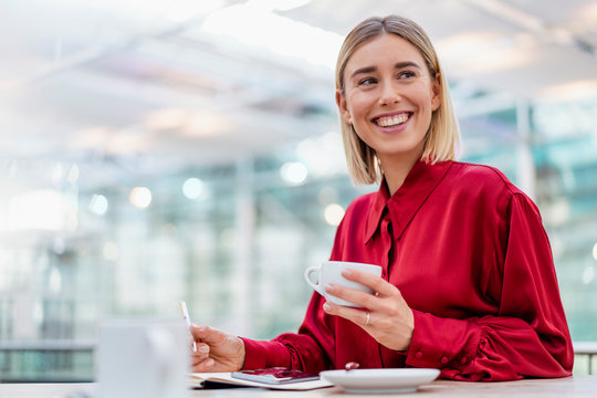 Happy young businesswoman taking notes in a cafe