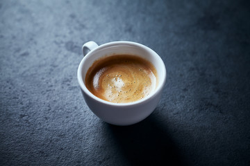 Cup of coffee on dark stone background. Copy space