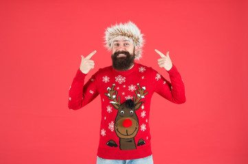 bearded man smiling on red background. funny man with beard in knitted sweater. cheerful hipster ready for xmas party. winter holiday celebration. cold weather fashion for men. happy new year