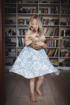 Blond little girl dancing with her Burmese cat at home