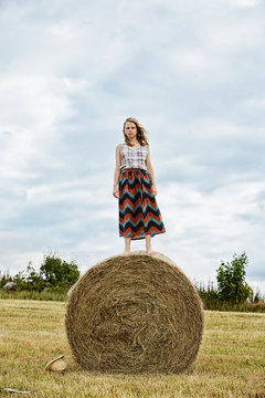 Girl standing on bale of hay