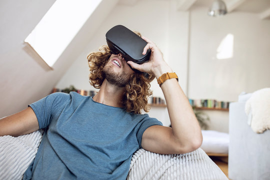 Young man wearing VR glasses at home