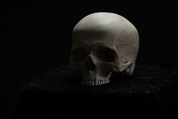 Skull lying on the altar in the dark on a black background.