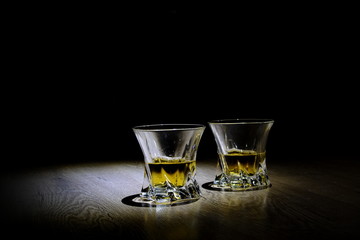two glasses of whiskey on black background