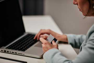 Young caucasian businesswoman sitting in her office and using credit card to pay subscription for licensed software.