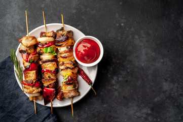 Meat skewers with grilled vegetables on a white plate on a stone background with copy space for...