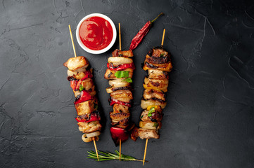Meat skewers with grilled vegetables on a stone background