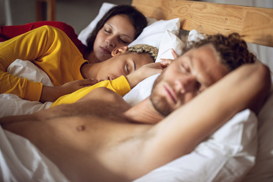 Three friends sleeping in bed at home