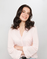 Obraz premium Portrait of smiling young woman with folded hand over white background